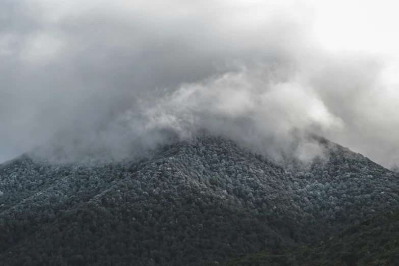 a black and white po of clouds rolling over a mountain