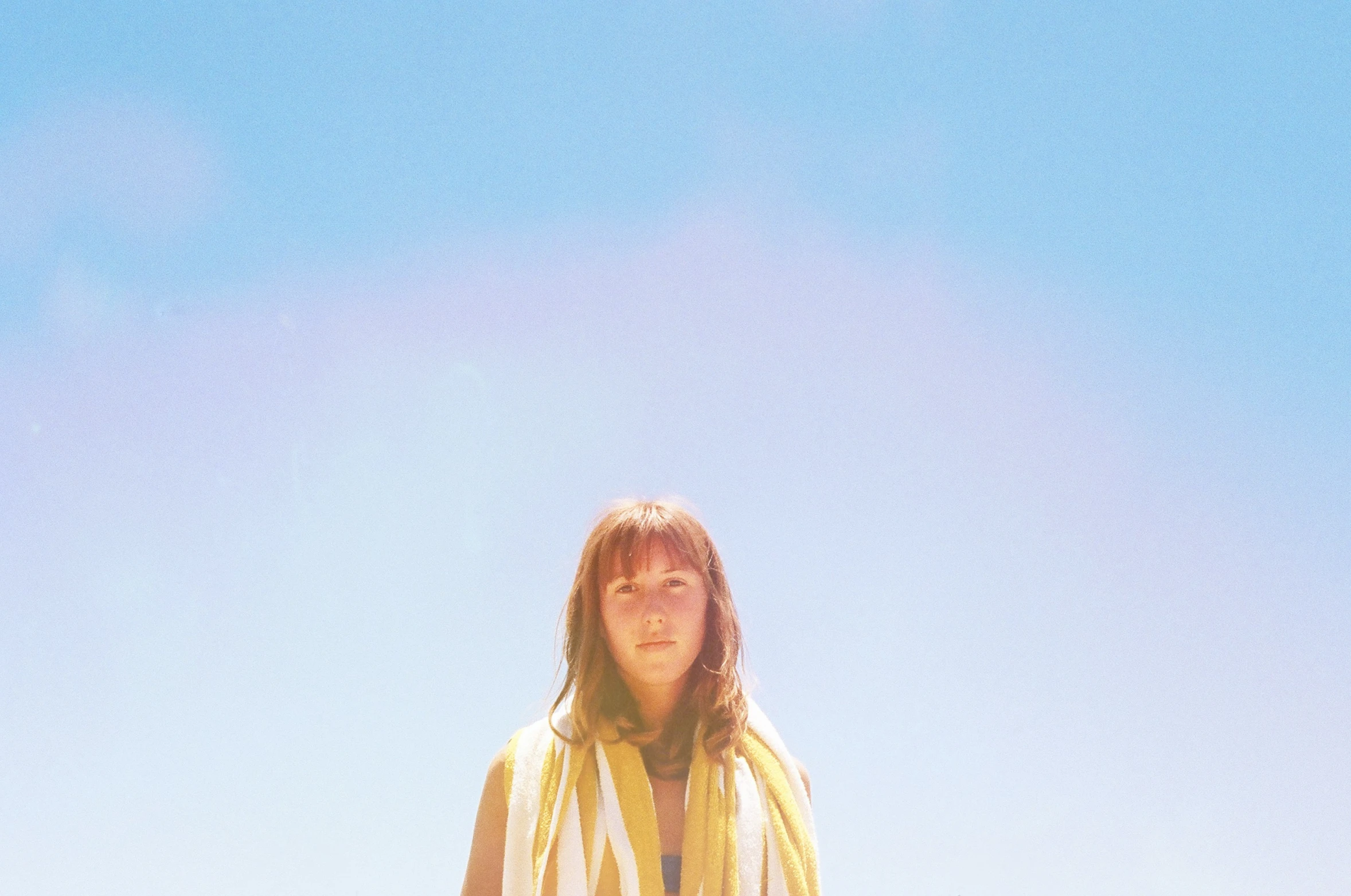 a woman standing next to a yellow kite in the sky