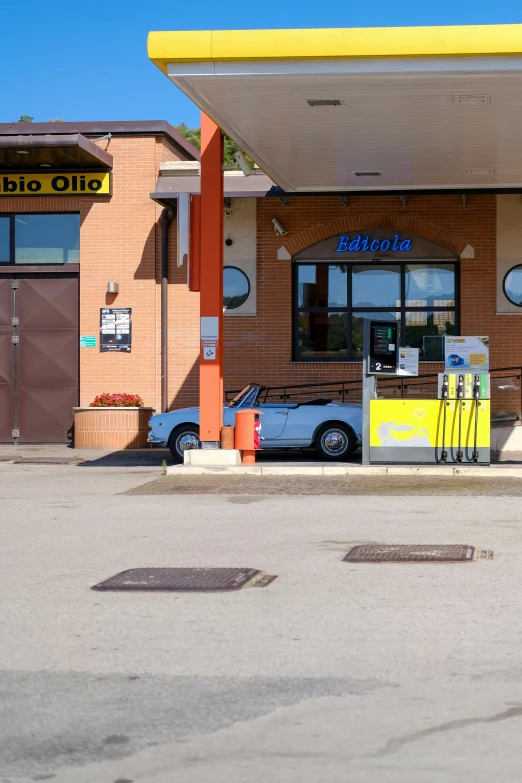 a car is parked in front of a building with gas pumps