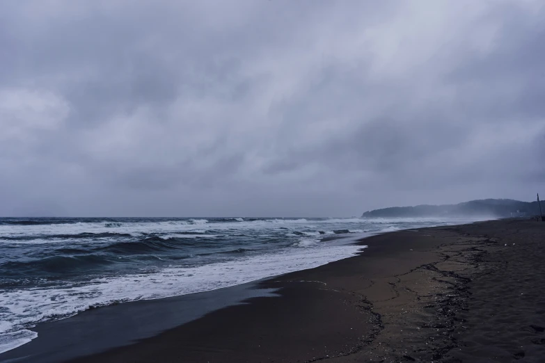 a black sandy beach under a cloudy sky