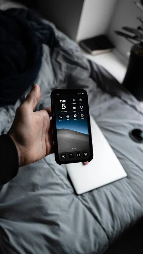 the person is using a smartphone to check on his bed