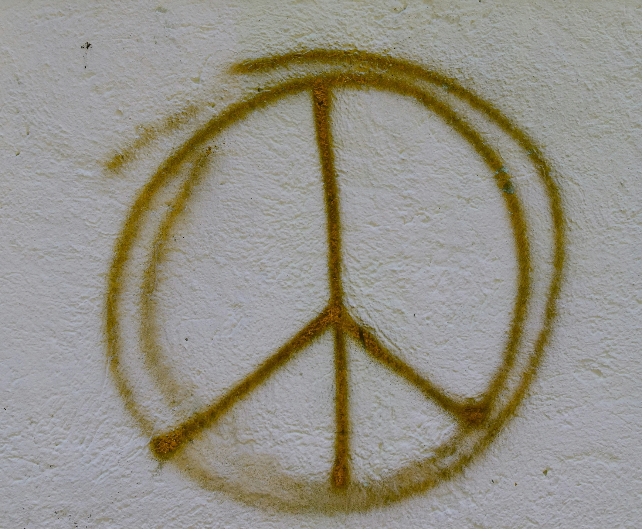 yellow speckled peace sign with faded edges on white wall