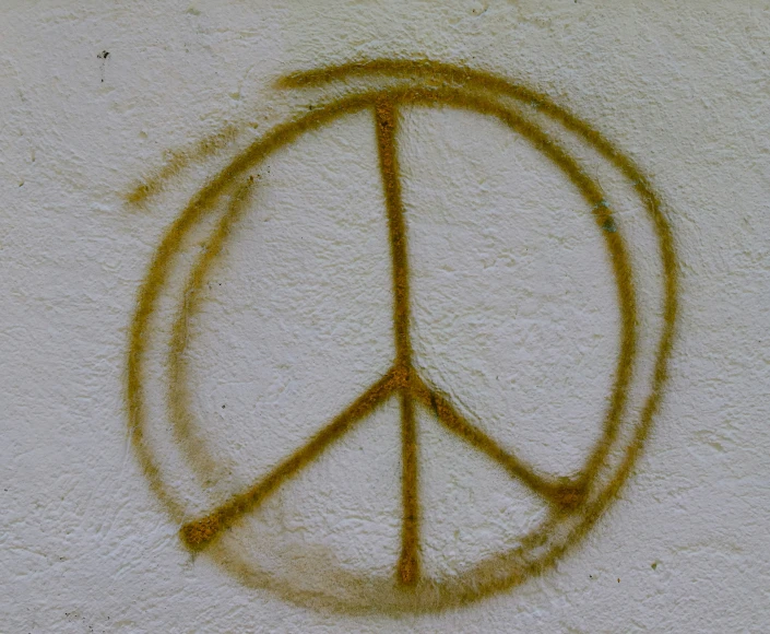 yellow speckled peace sign with faded edges on white wall