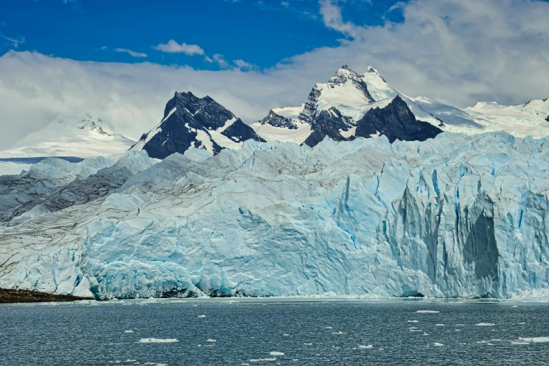 a large glacier in front of a snowy mountain