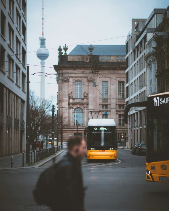 a man on the sidewalk is near a yellow bus