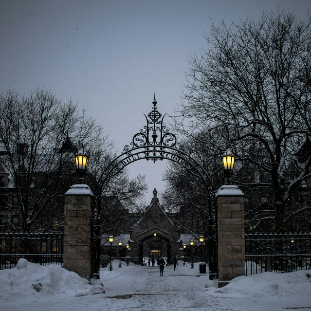 two statues in the snow in front of an arch