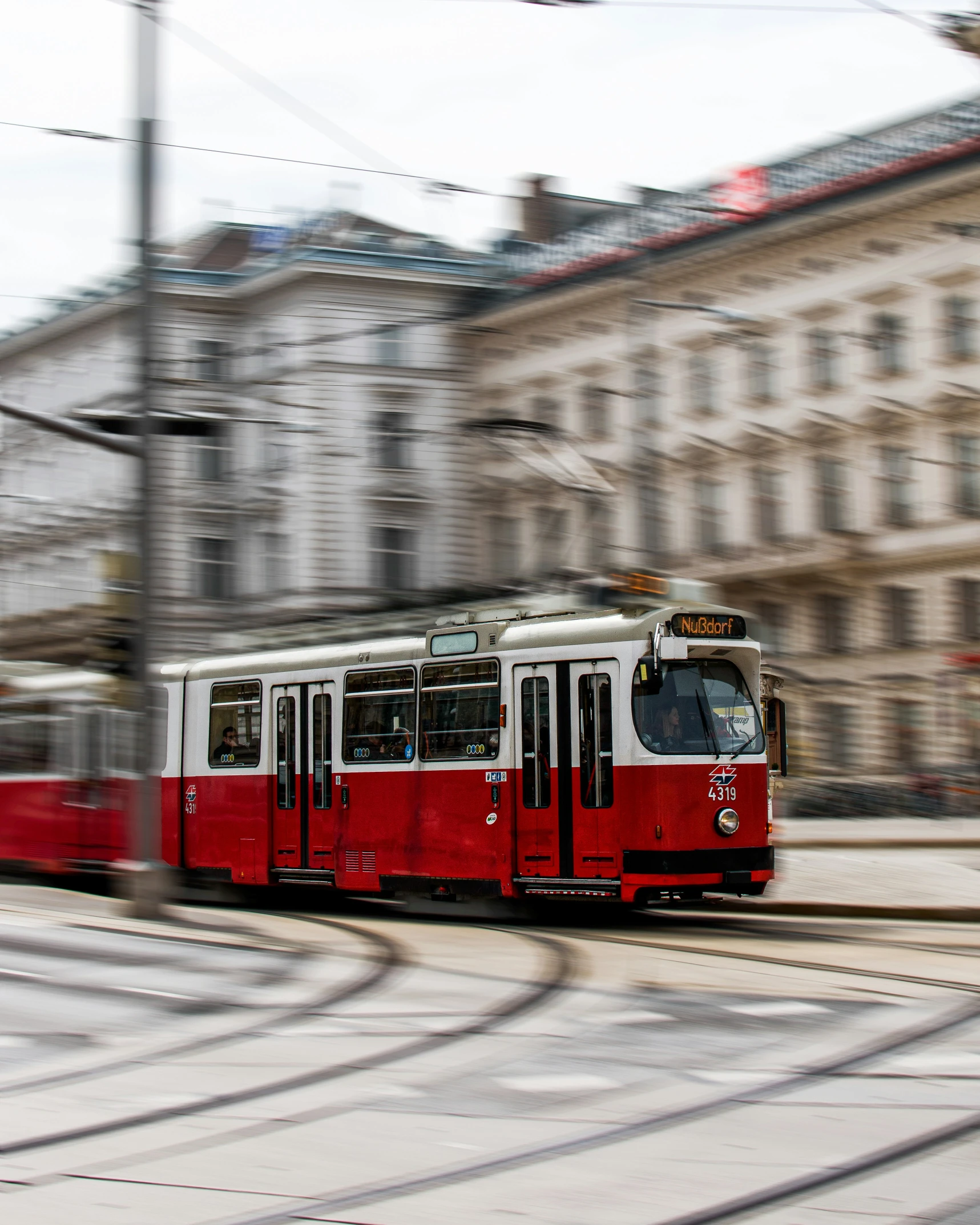 a red and white tram is coming down the track