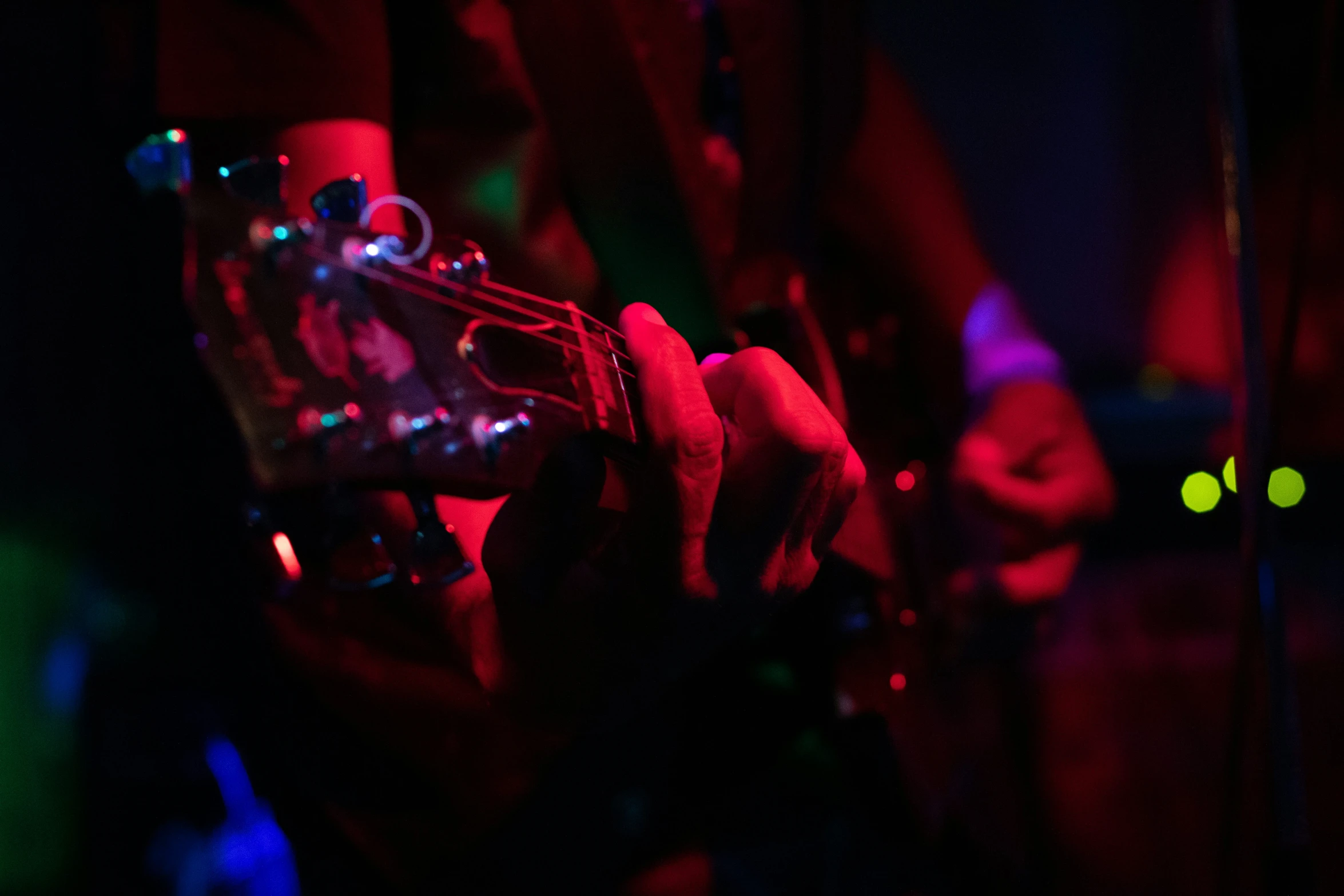 a person is playing guitar with colored lights