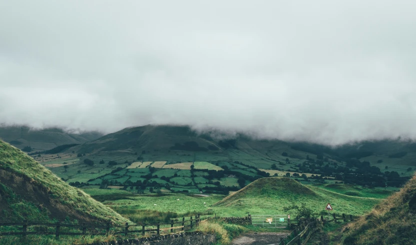 a green hill landscape with the clouds above it