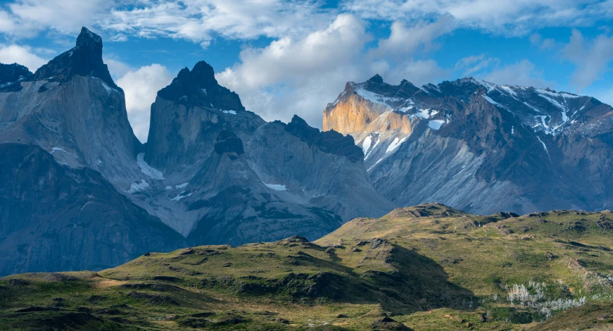 mountains with snow in the middle surrounded by green hills