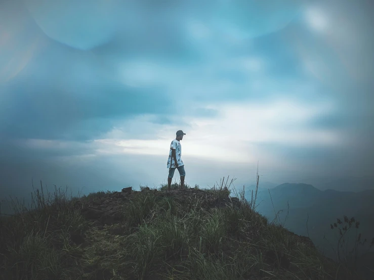 the man standing on the mountain has a hat