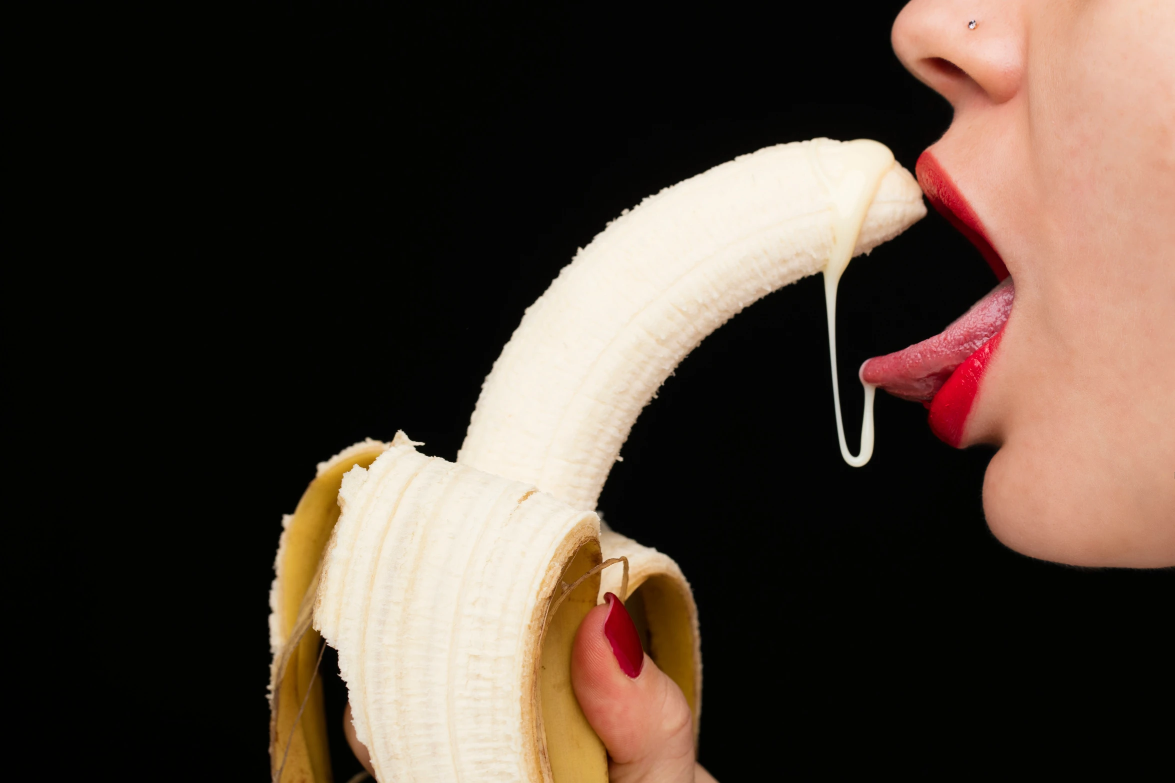 the woman is biting the peeled banana off her mouth