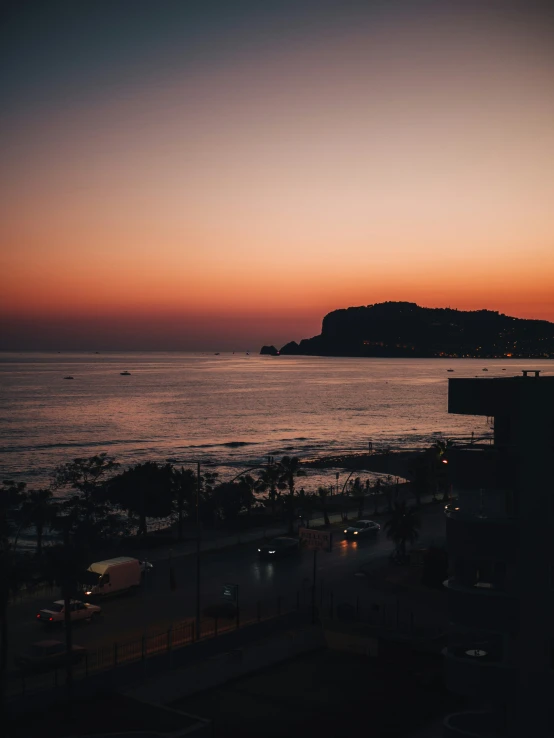 a view of the sea at dusk with light on the buildings