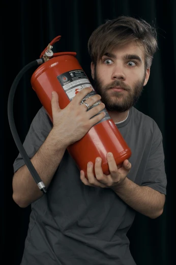 the man is holding a fire extinguisher to his face