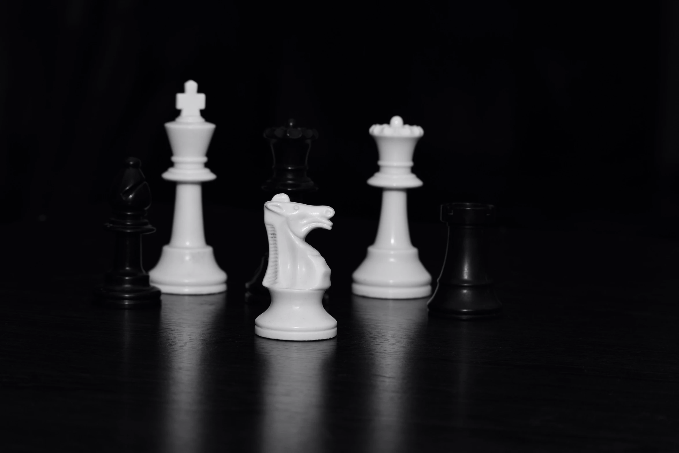 various sized chess pieces sitting on a dark surface
