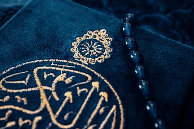 a close up image of a gold and black tasseled muslim prayer shawl