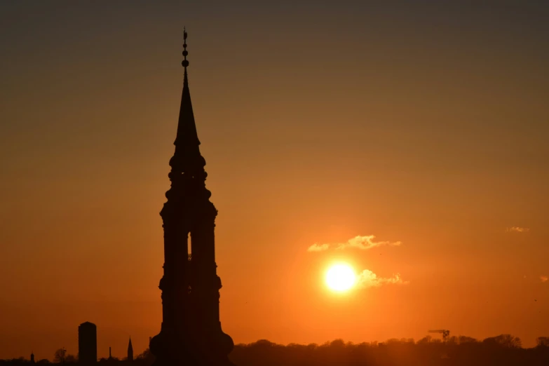 the sun sets behind a church tower with steeples