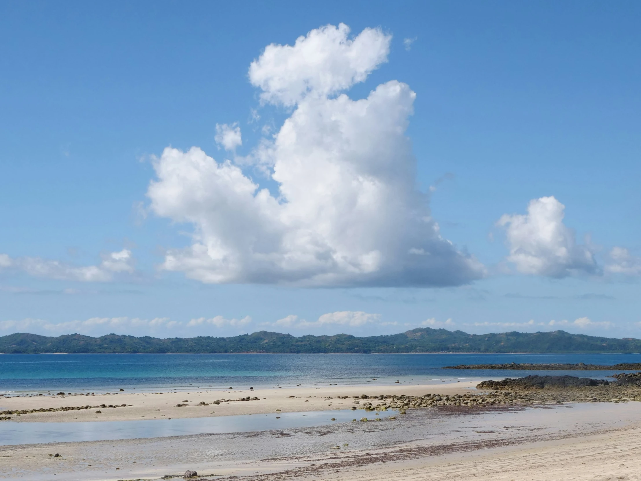 some blue water a sandy beach and some clouds