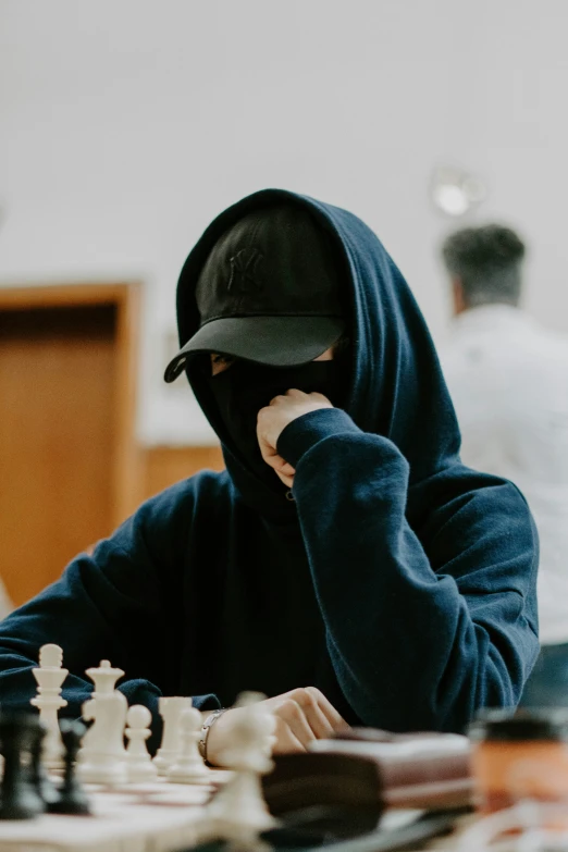 a man wearing a hood, playing chess