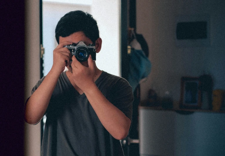 a boy holding a camera taking a picture