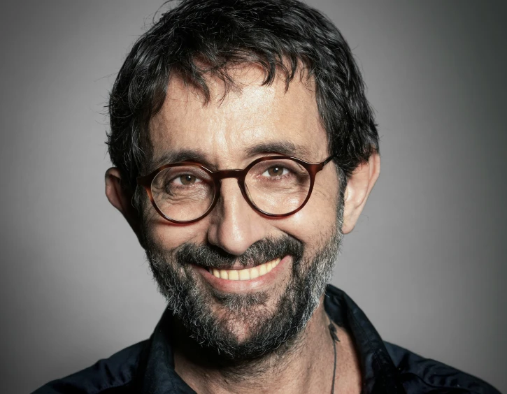a man with glasses on smiling and wearing a shirt