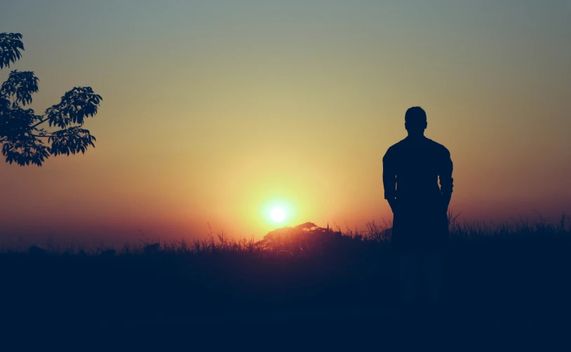 a silhouette of a man is shown against a bright orange sunset