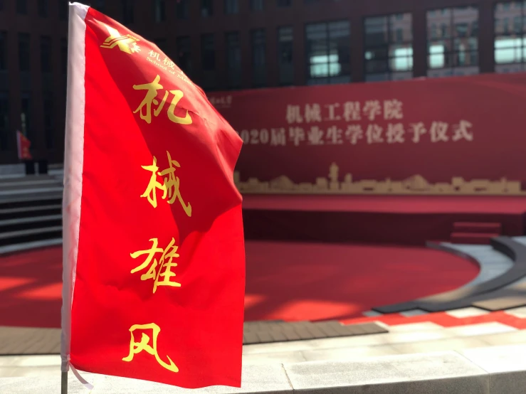 two flags with chinese writing and some buildings in the background