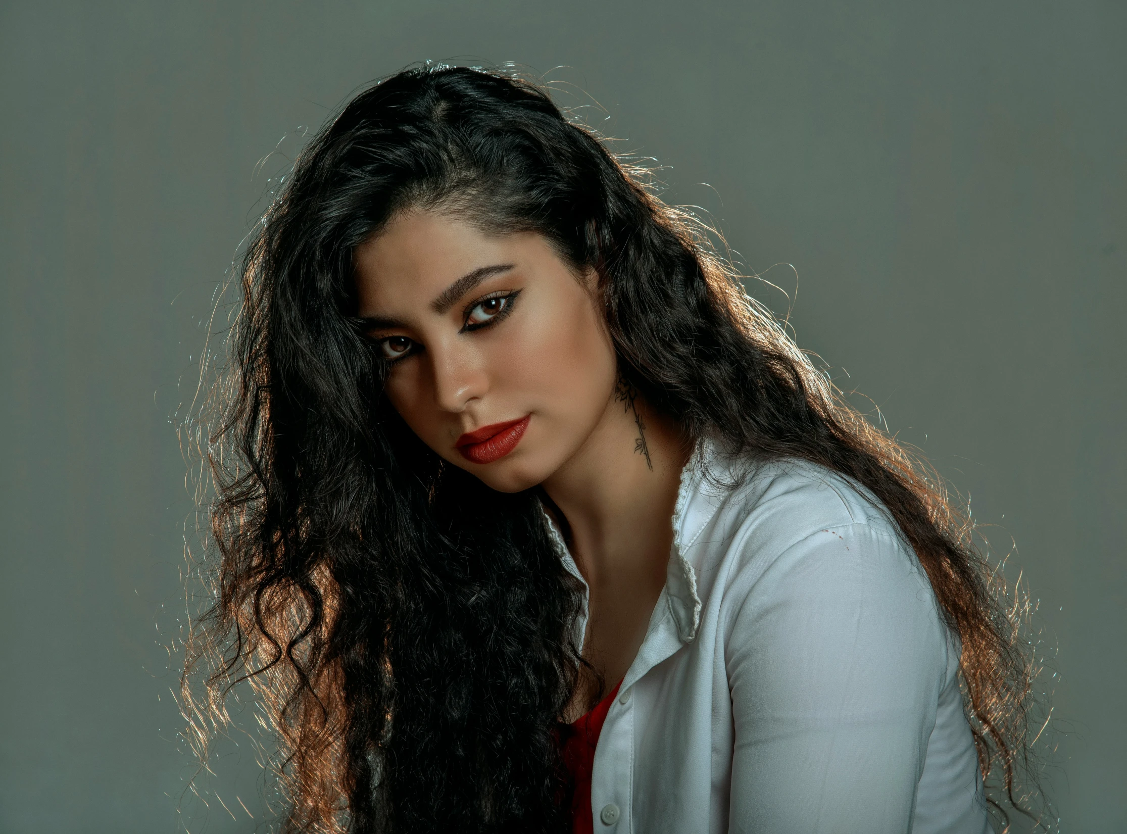 a woman posing with long dark hair and a white top