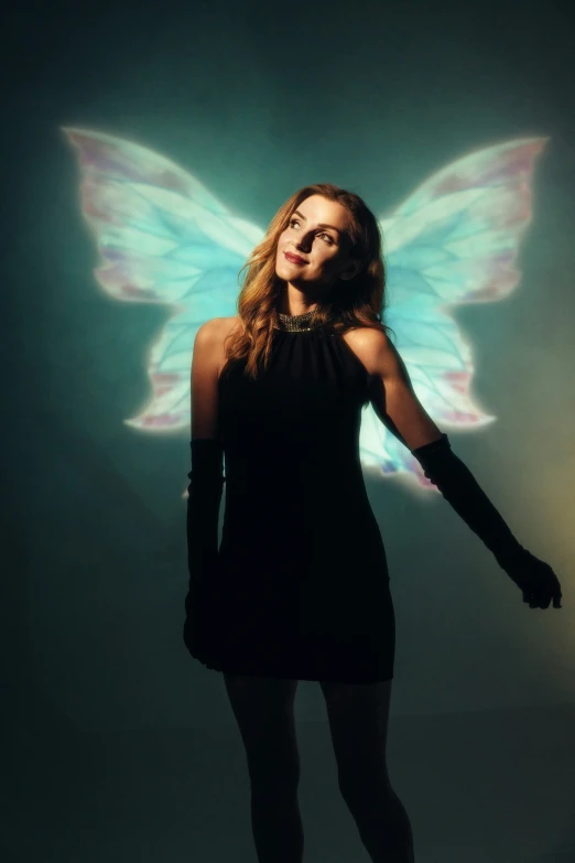 a beautiful woman dressed in black posing for a picture with a erfly wings