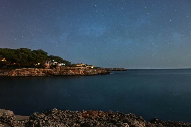 stars and light houses over the water at night