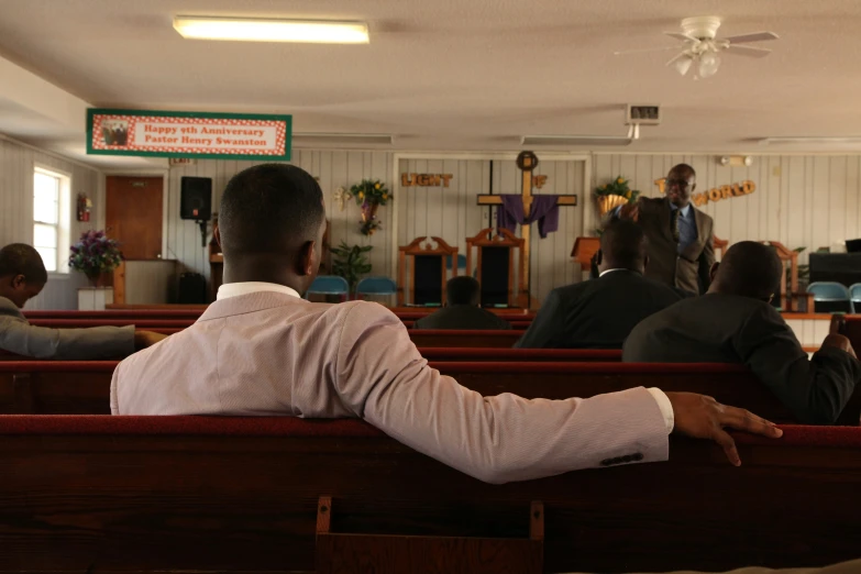 people in church pews during service with a man standing