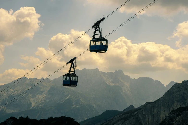 two electric gondolas in front of mountains with clouds