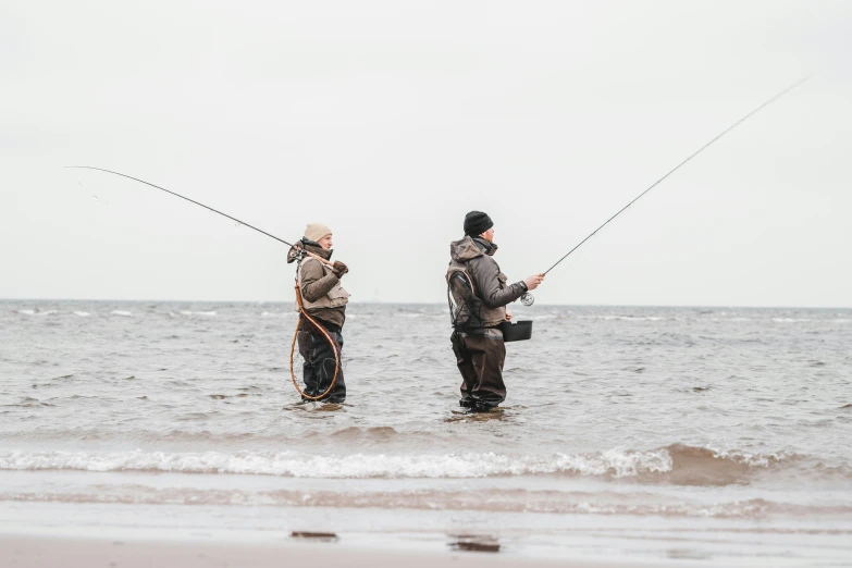 two men standing in the water fishing while holding on to ropes