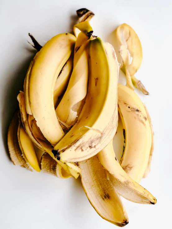 several bunches of ripe bananas on a white surface