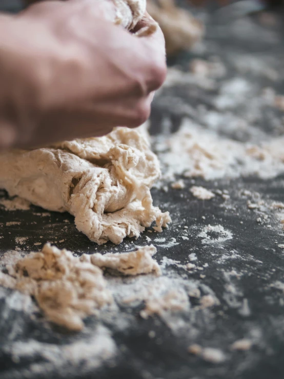 the hands of two people knead dough on a table