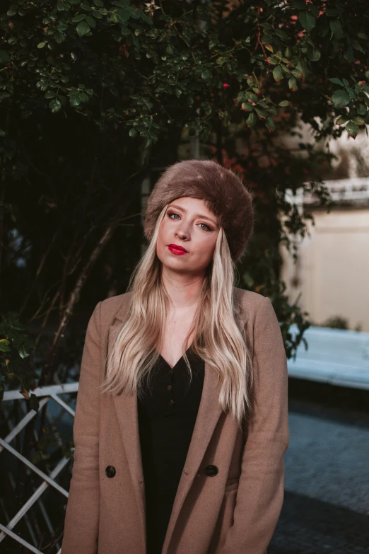 a woman wearing a brown jacket and hat