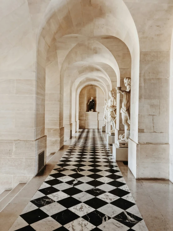 an archway has checkerboard tile flooring, and statues on either side