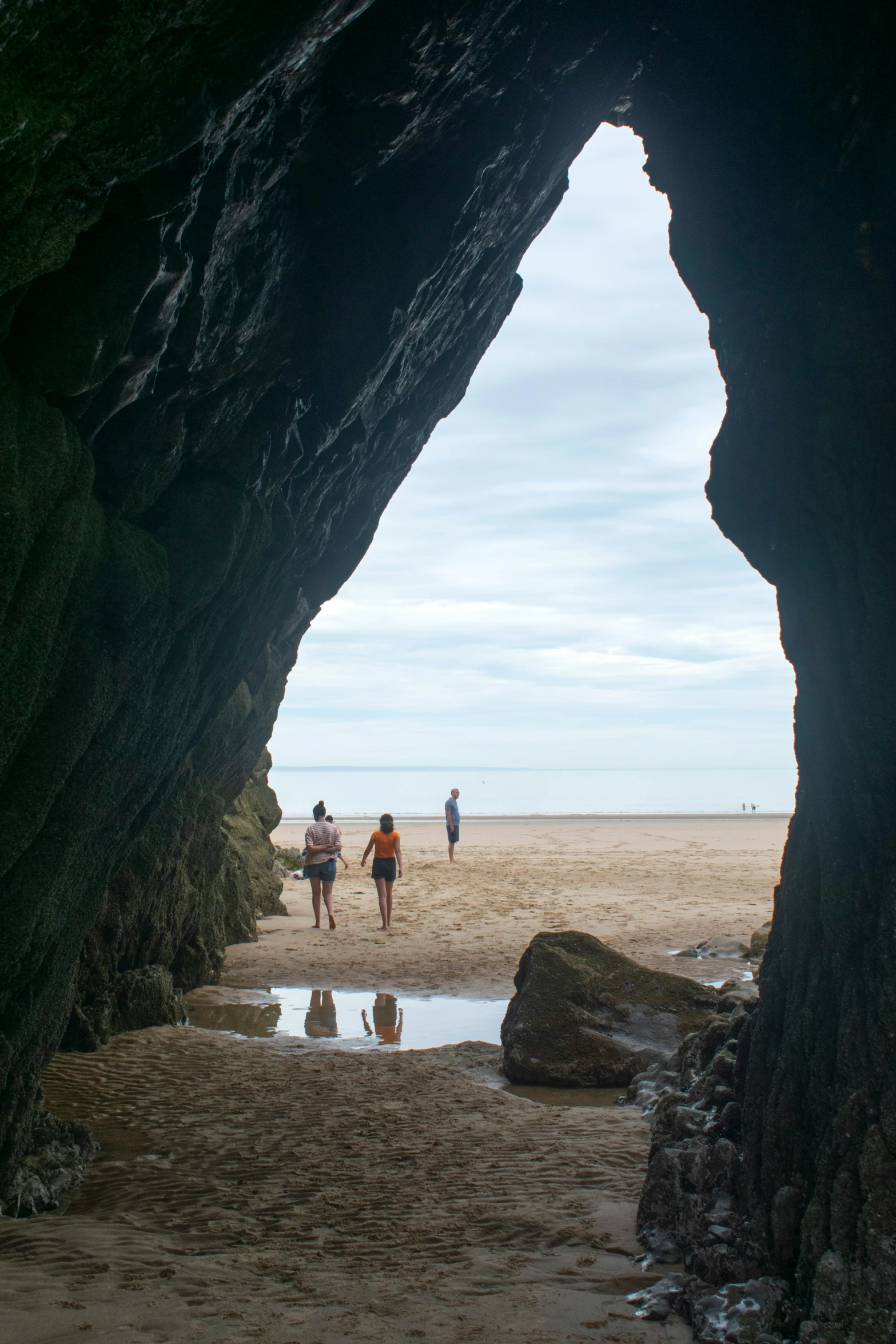 a group of people walking through a cave next to a body of water