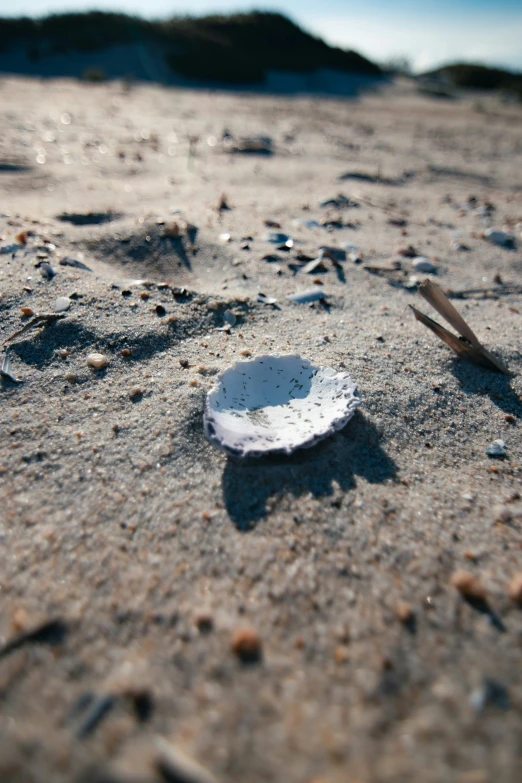 a white object sitting in the sand next to two tongs