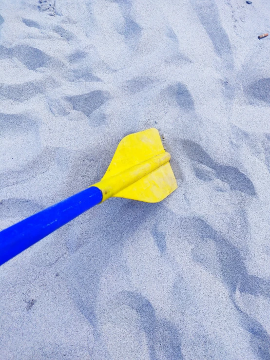 a yellow plastic oar lying on a beach