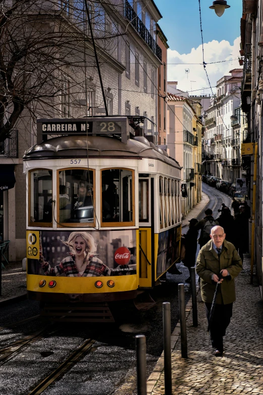 an old woman walking down the street past a tram