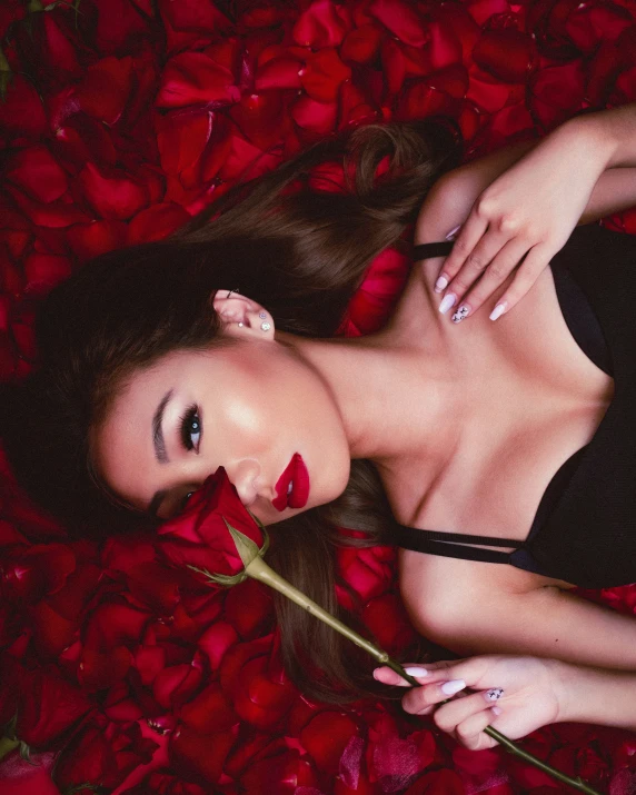 an attractive lady holding a rose on the bed