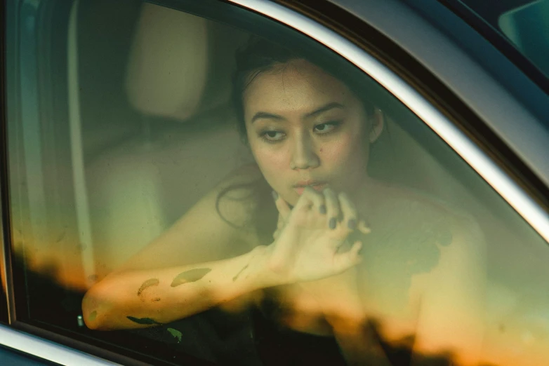 a young lady sitting in her car while looking out the window