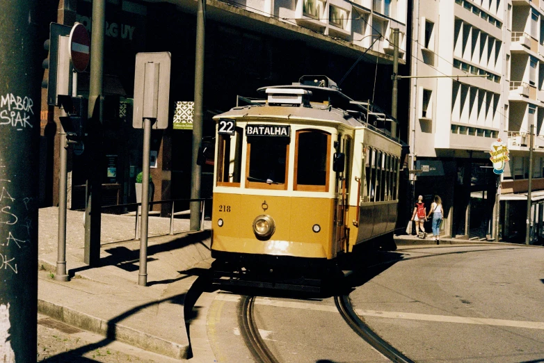 an old yellow tram traveling down the road