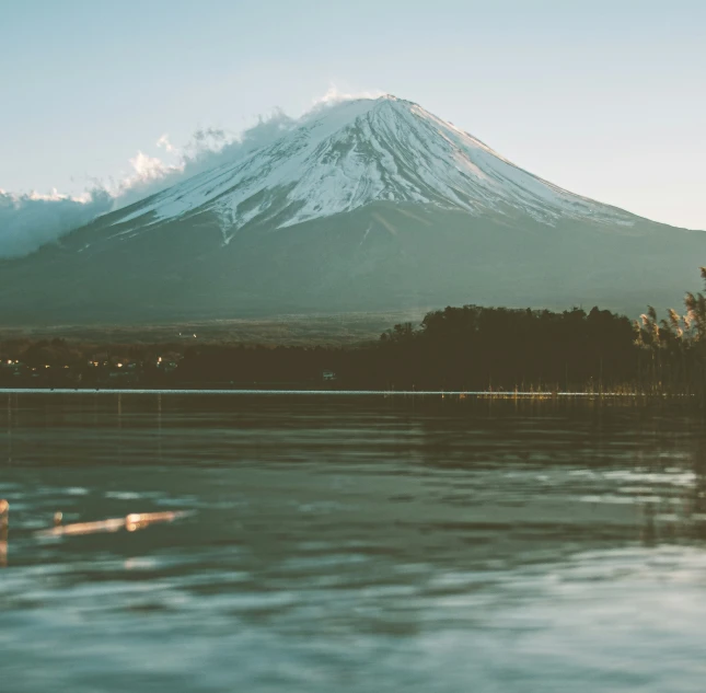 two boats floating on a river near a tall mountain