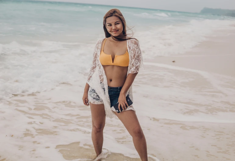 a woman wearing a bikini standing on a sandy beach