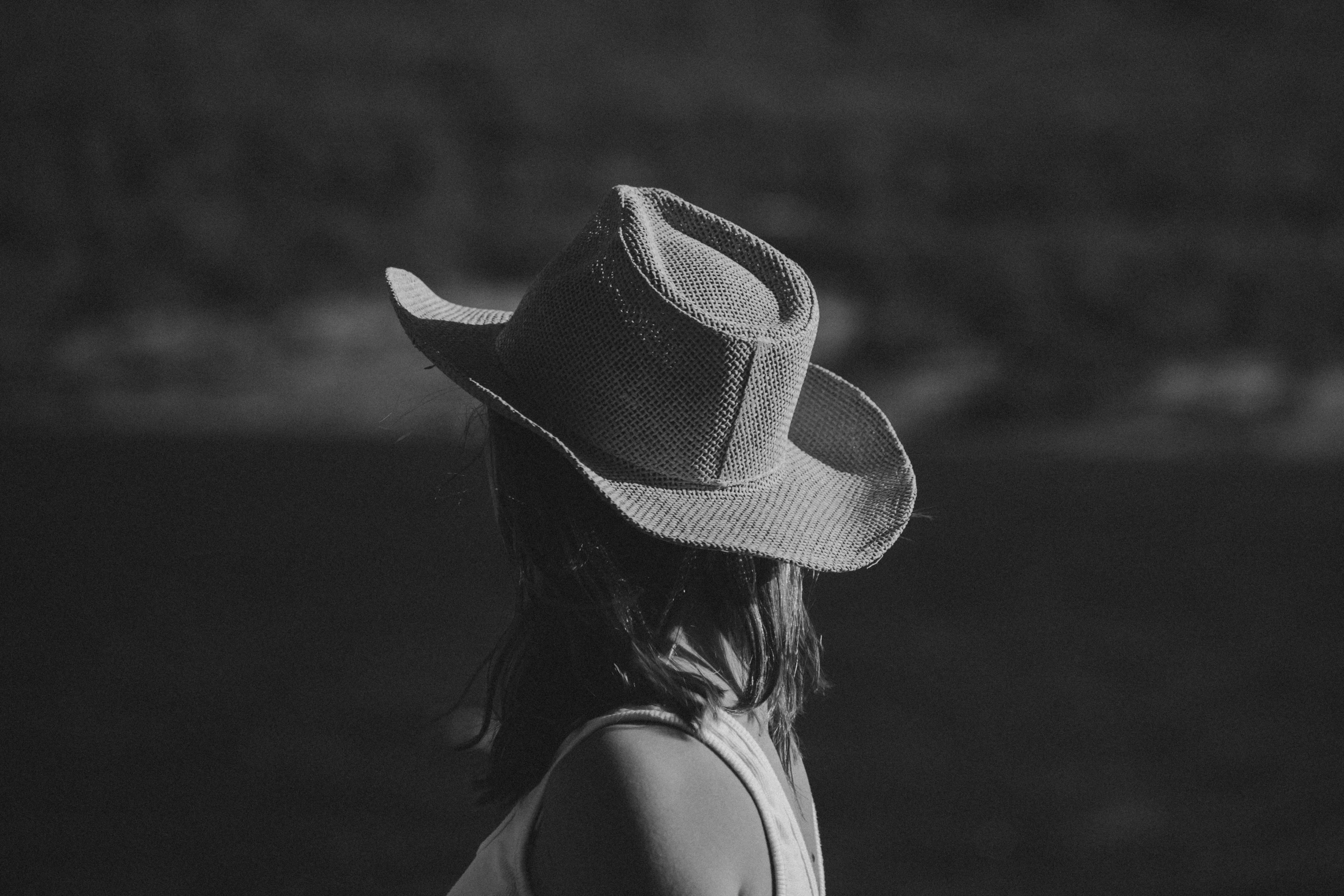 a woman in a white dress standing outside wearing a hat