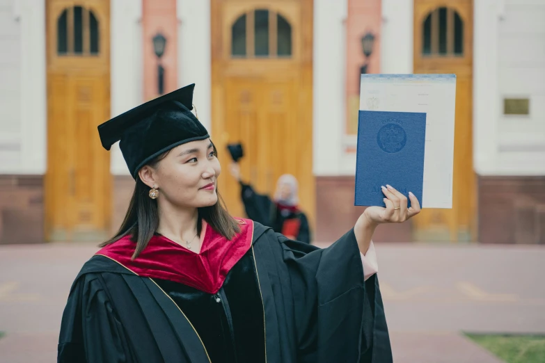 a woman holding up her diploma outside a building