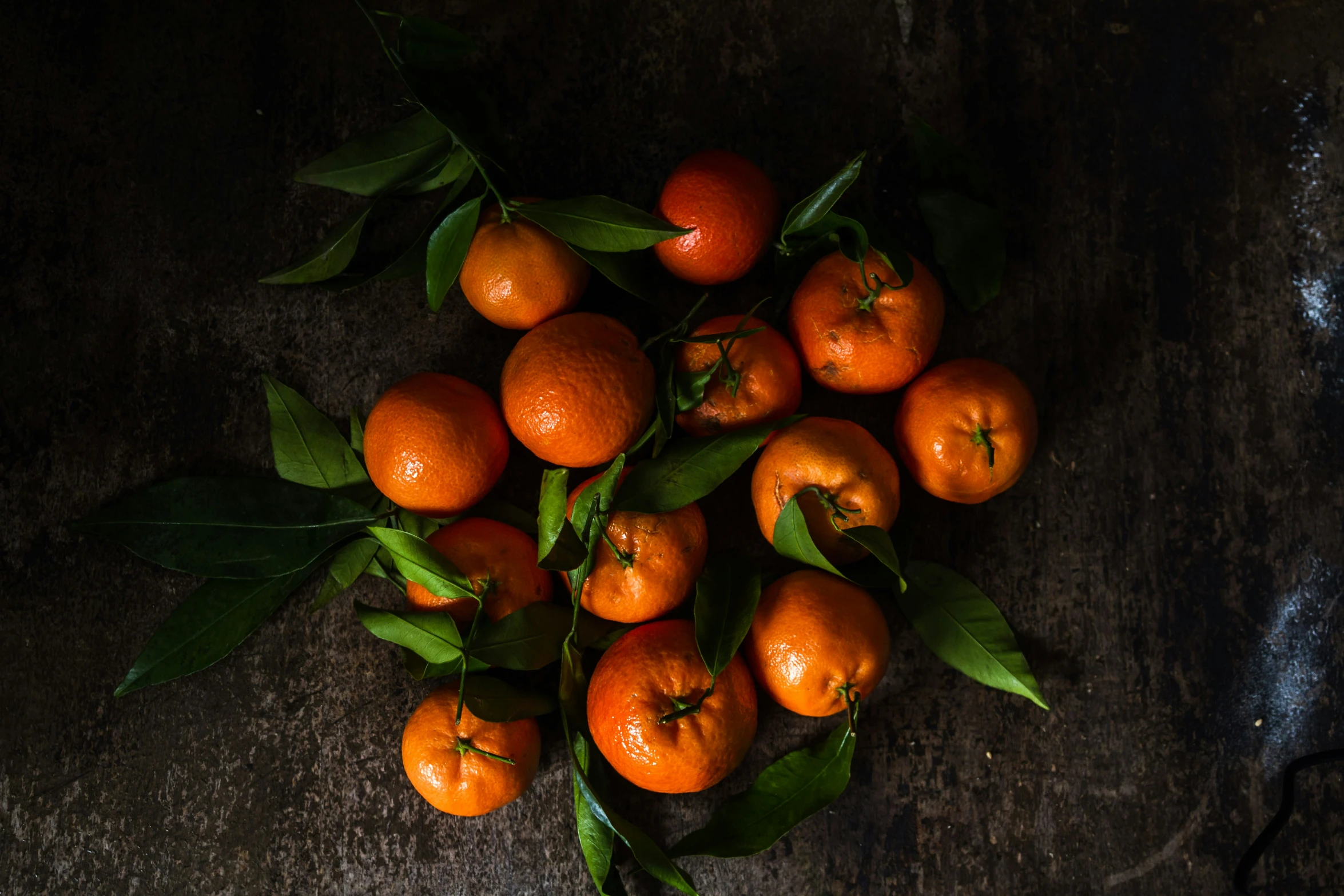 oranges with green leaves are laying on top of the table