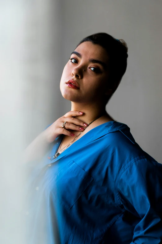 a woman leaning on a wall in a blue dress